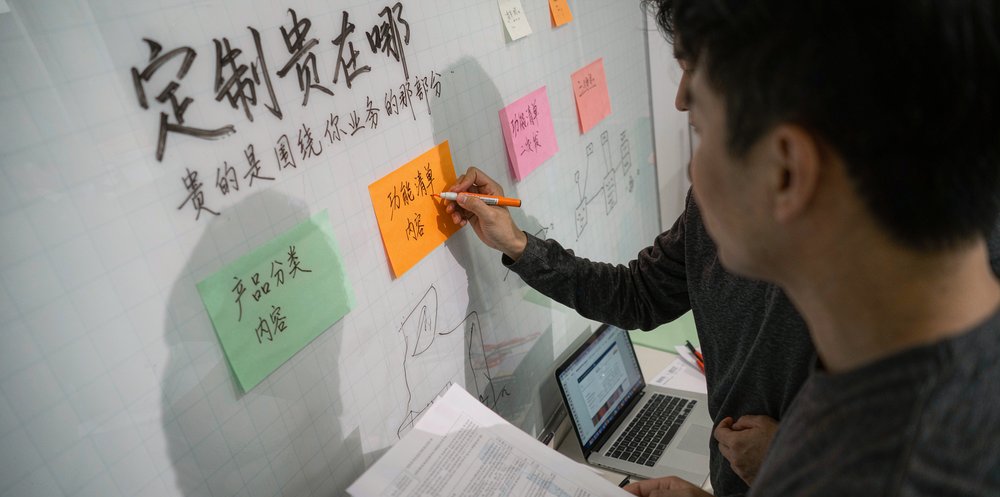 团队在白板上梳理定制开发的功能清单,算清贵在哪