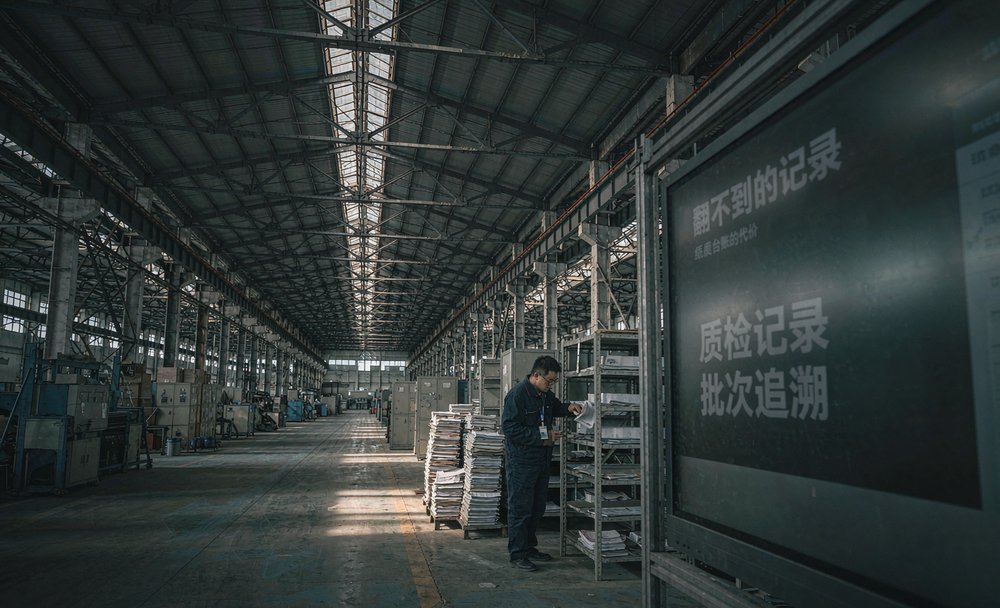 汽配厂车间里质检员翻找纸质质检记录,制造业数字化改造前的样子
