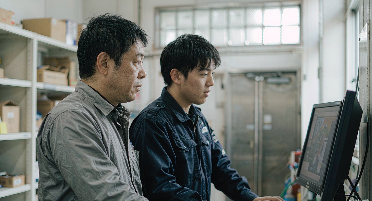 办公室里,老板和技术人员一起看电脑上的AI回答
