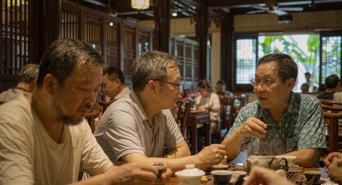 茶桌边上几位陶瓷厂的老板围坐聊天,桌上摆着茶具